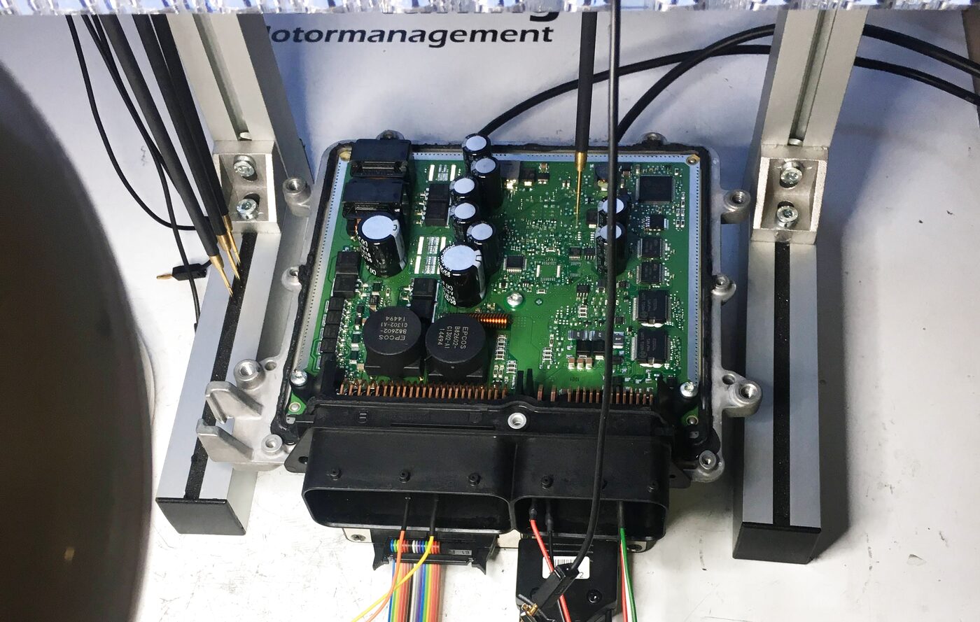 Geöffnetes Motorsteuergerät auf der Werkbank, Platine mit angeschlossenem Programmieradapter
